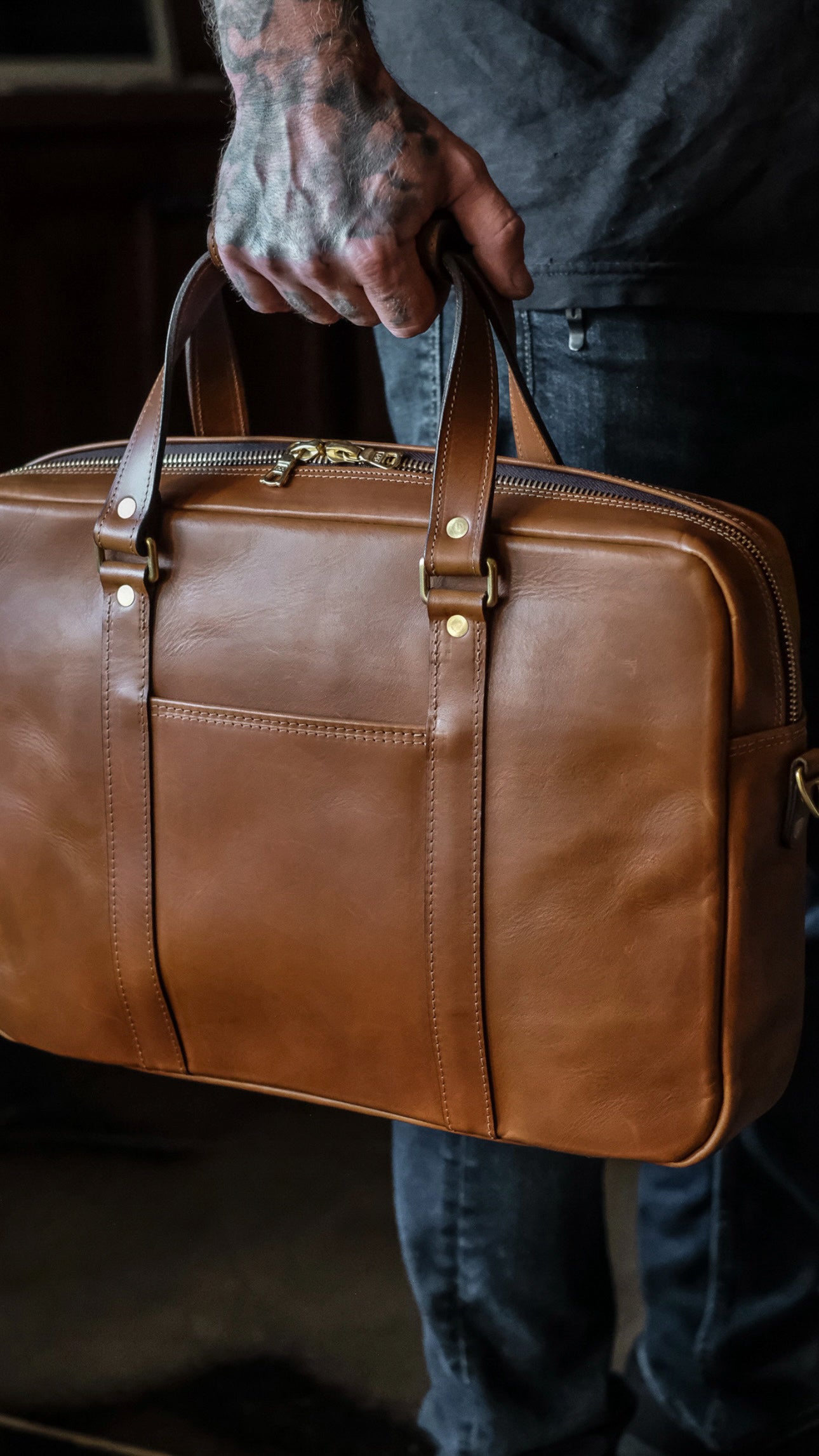 Side angle of handmade leather briefcase with dual handles in hand