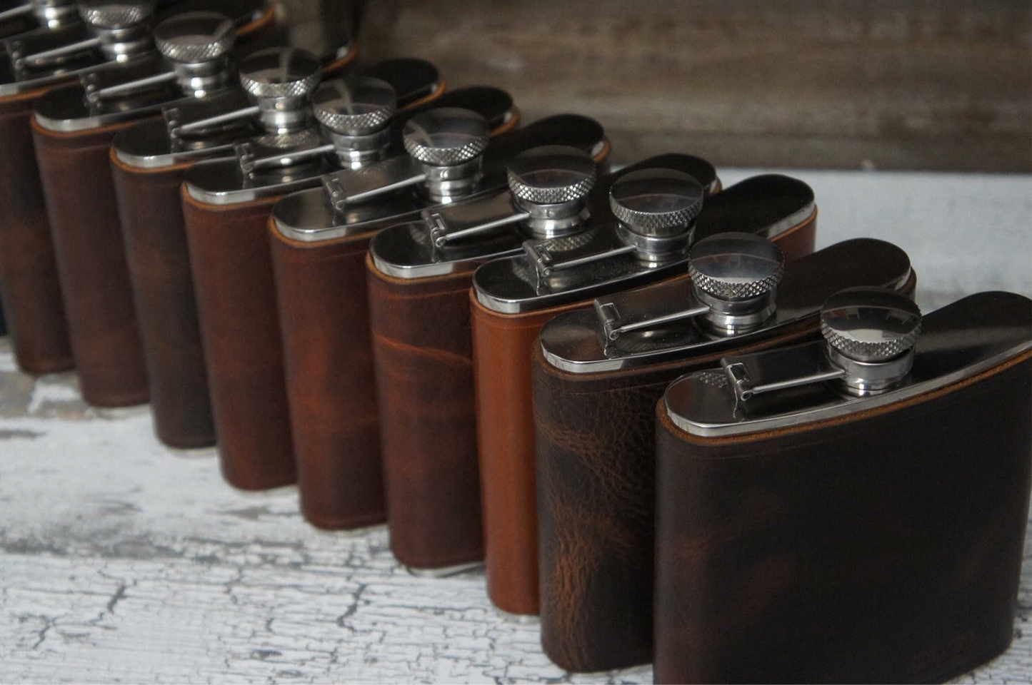 Row of leather Wrapped flasks - handcrafted by Gunnar & CO, shown in various full-grain leather tones