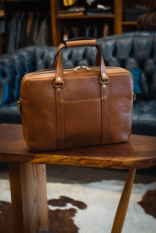 Handmade Italian Vachetta leather briefcase on wooden table — full front view