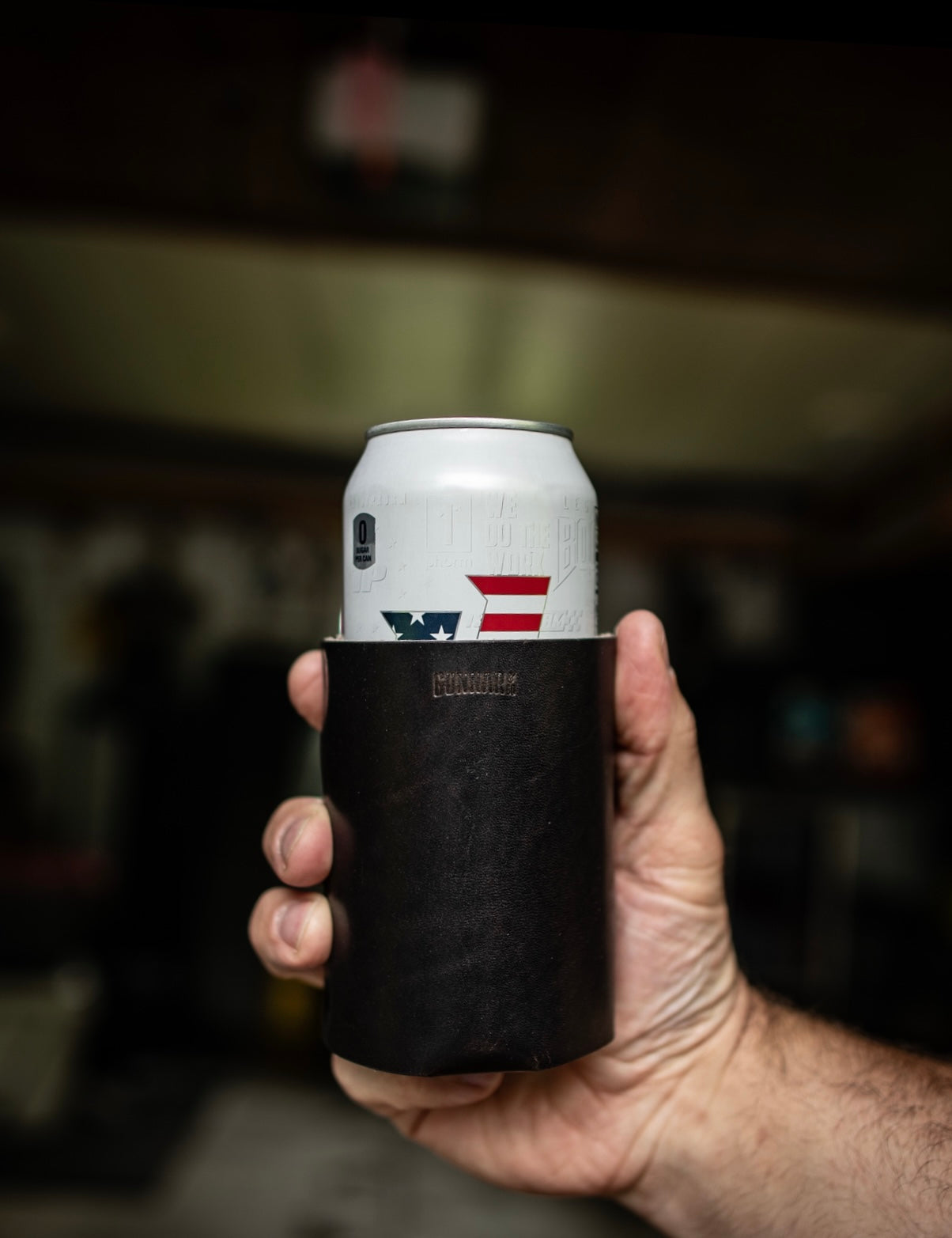 Close-up of hand holding brown leather can wrap with can featuring Texas flag design