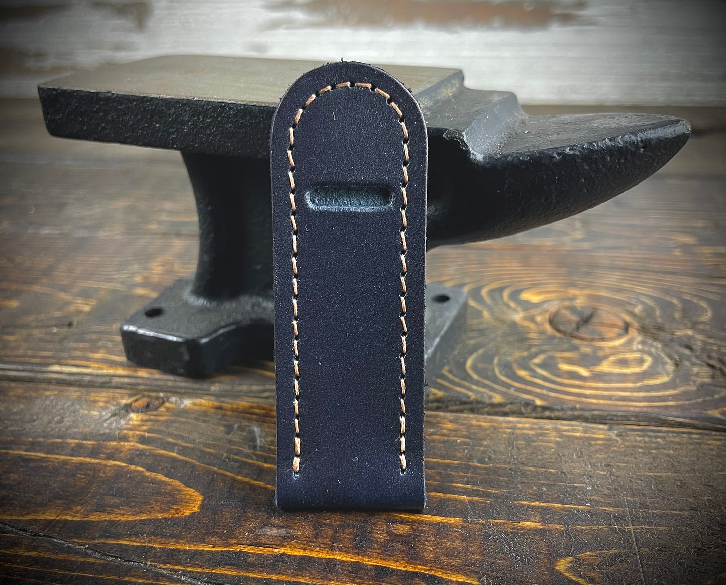 Navy blue leather toothpick holder standing upright on a wood and metal surface