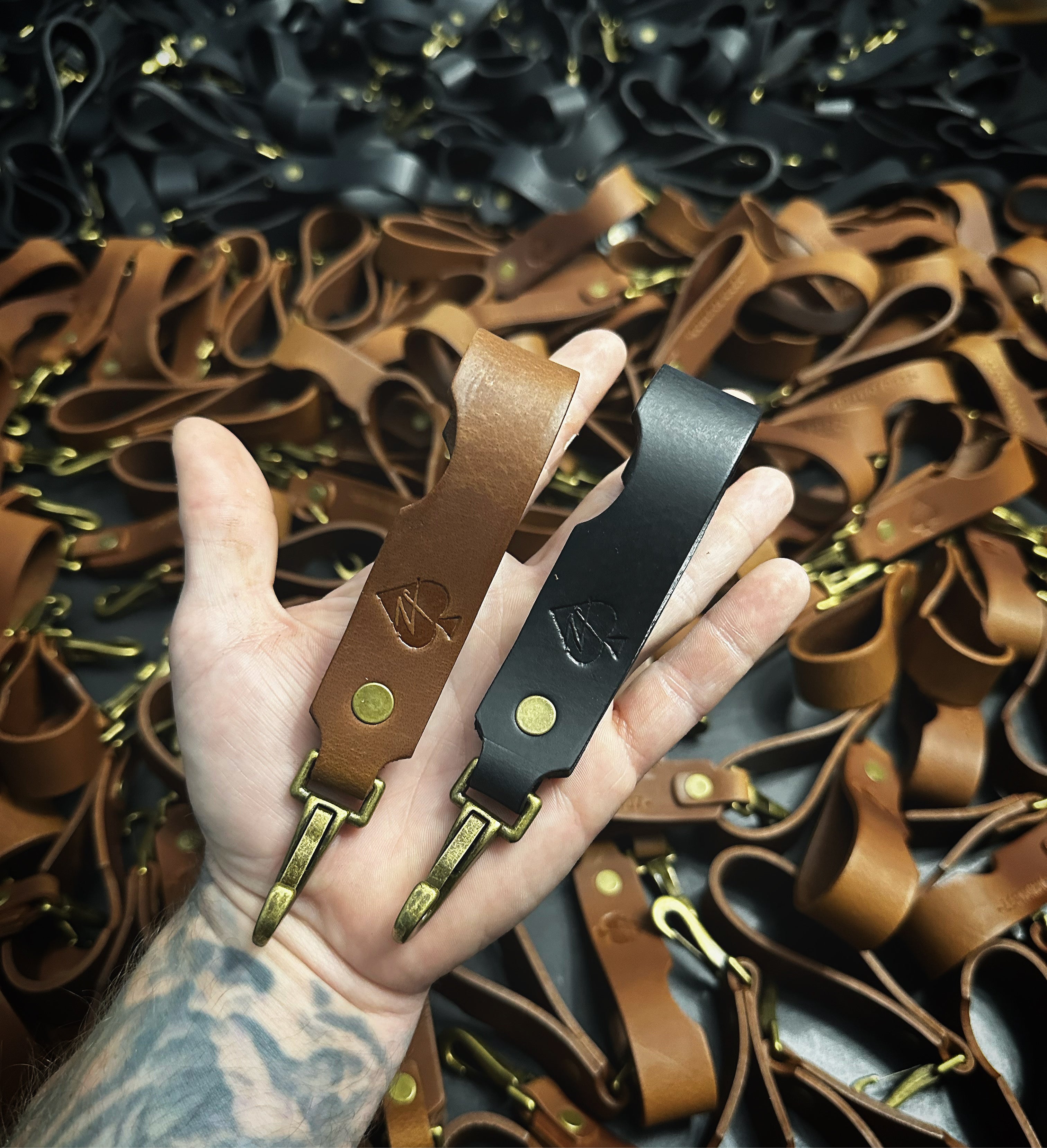 Bulk order of Gunnar & Co. leather key fobs in black and brown, featuring custom stamped logos and solid brass hardware, handmade in Texas.