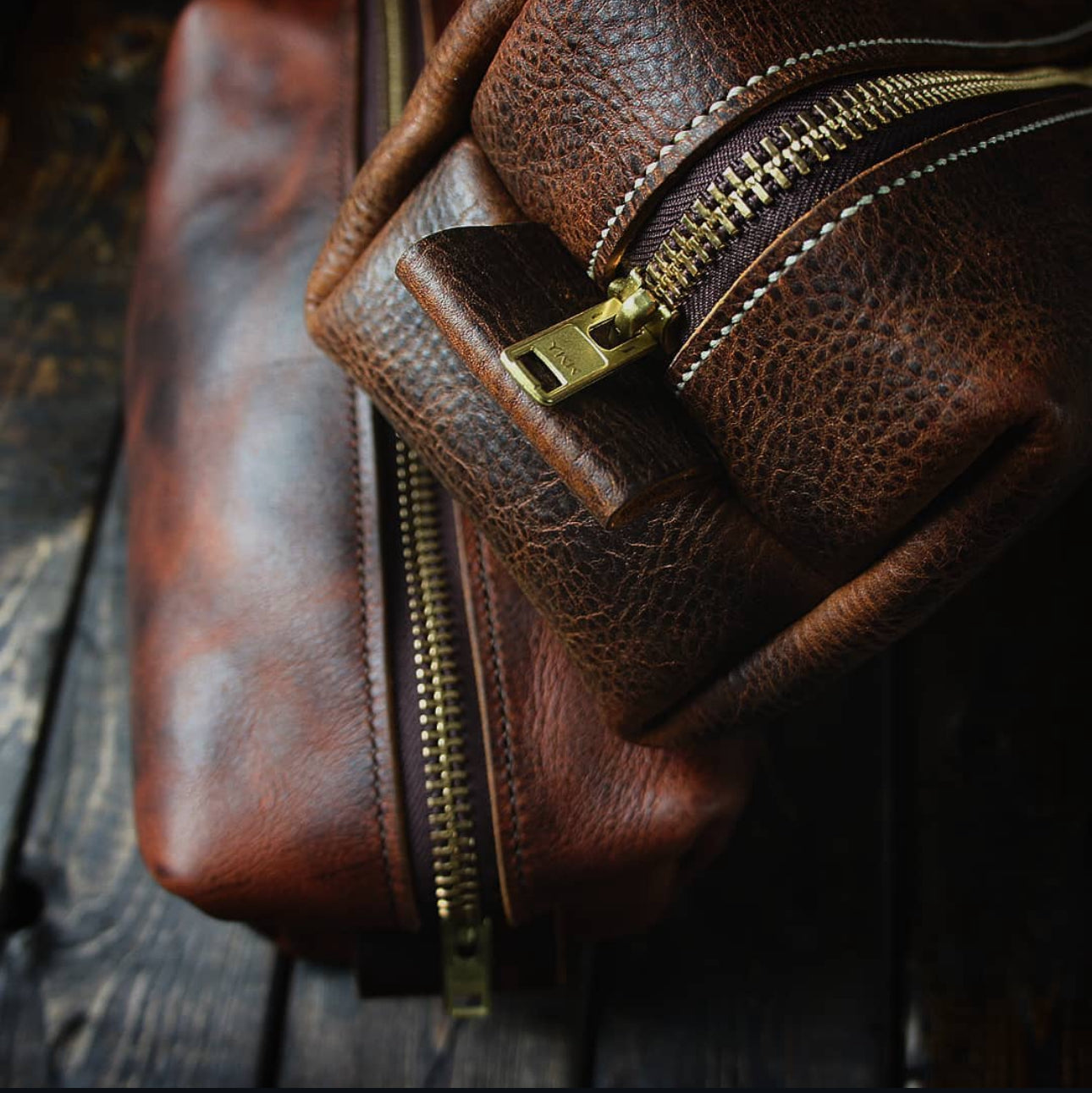 Close-up of a brown full-grain leather Dopp kit with a brass zipper, showcasing the rich texture and sturdy stitching.