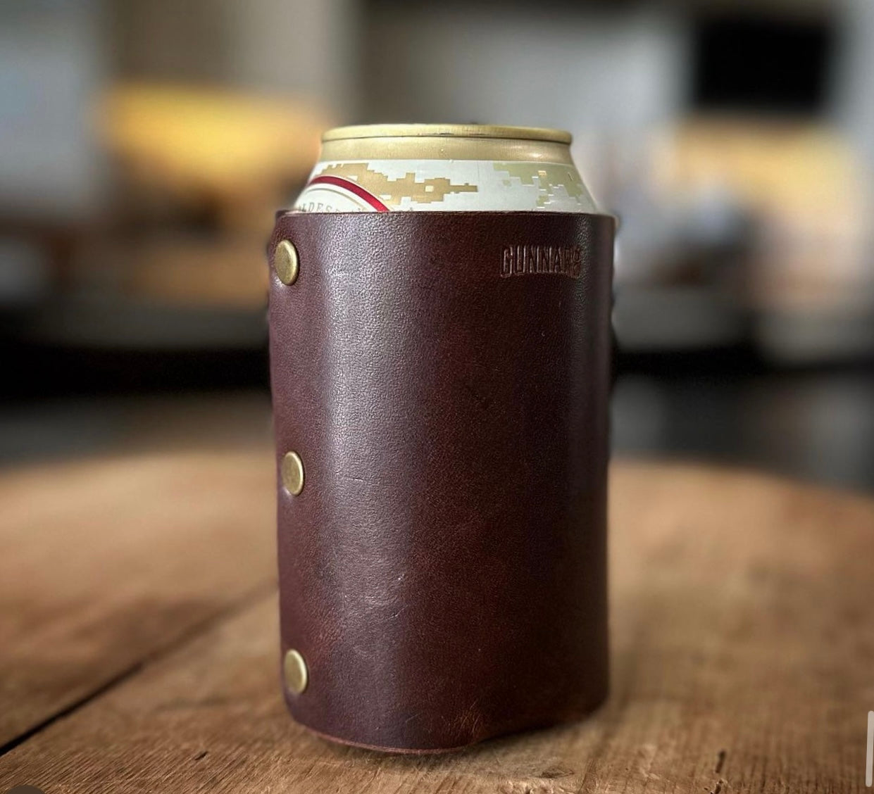 Brown leather can wrap on wood surface with a can inserted, angled side view
